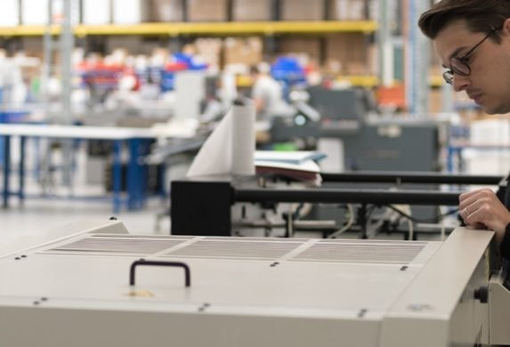 Man working on a printer at the MOO manufacturing facility