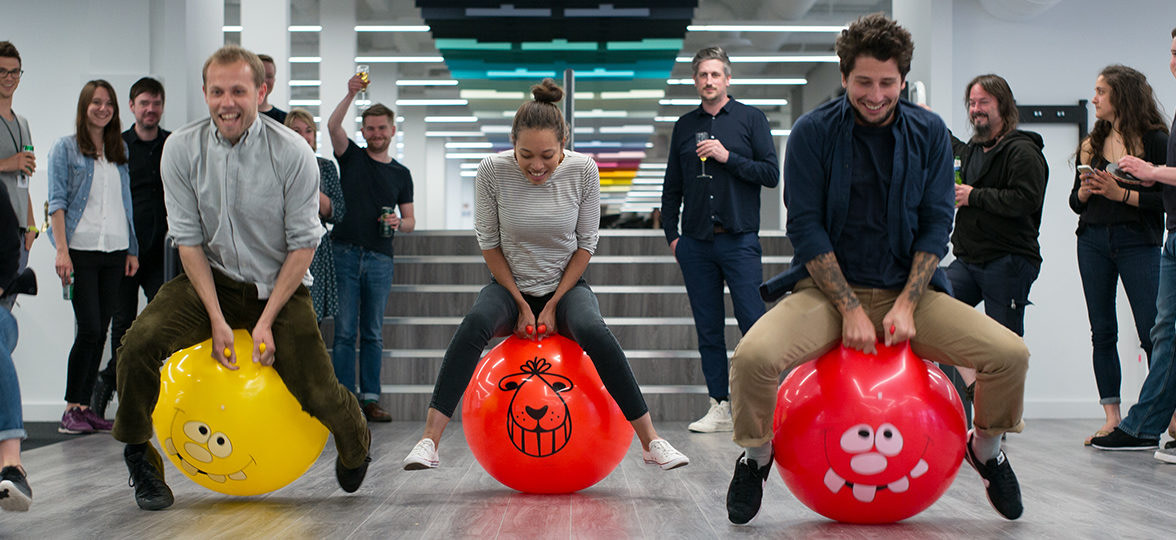 MOO employees using colorful space hoppers in the office showing a positive company culture and work life balance