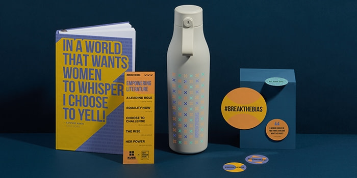 Event collaterals including a custom notebook, a water bottle, stickers and an event program for an International Women's Day event