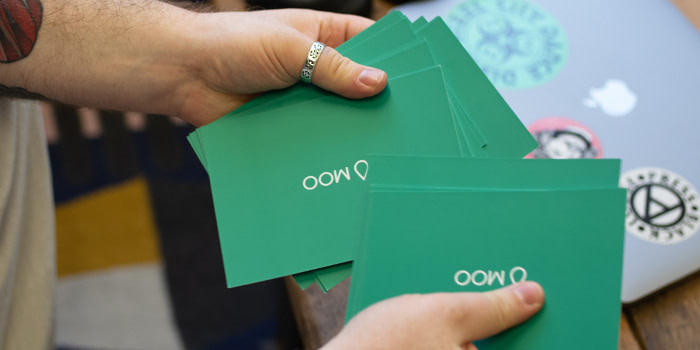 Hands mixing green question cards from MOO