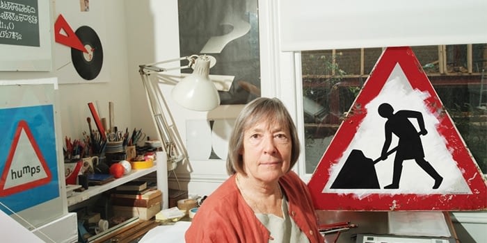 Margaret Calvert iconic female designer being photographed in front of her work for UK road signs