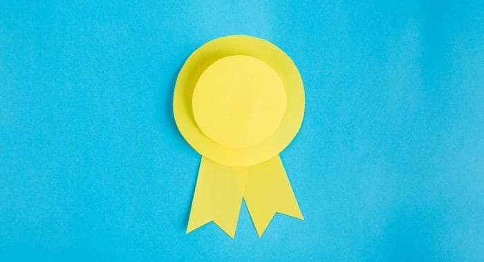 Yellow rosette made of paper on blue background