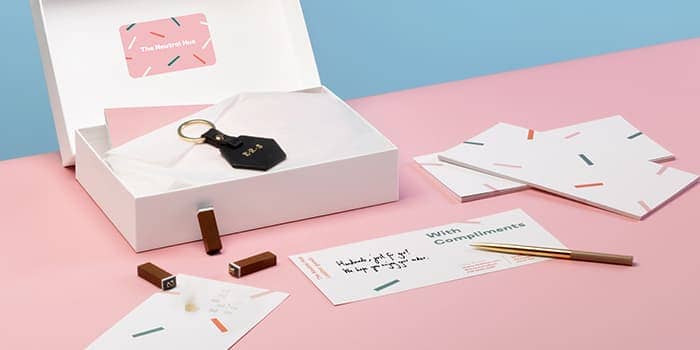 Open white box with a key ring and a sticker. There are compliment slips with handwritten thank you notes around.