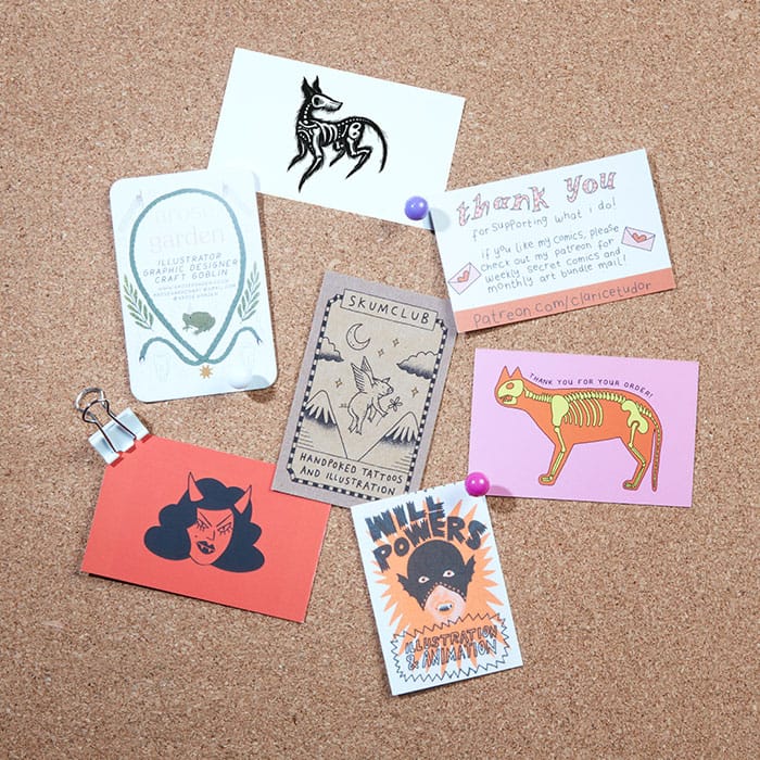 7 artist business cards on a cork board