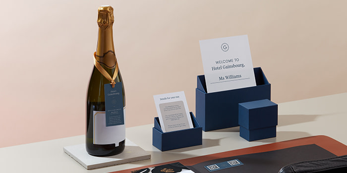Blue presentation boxes used to display flyers and cards next to a champagne bottle