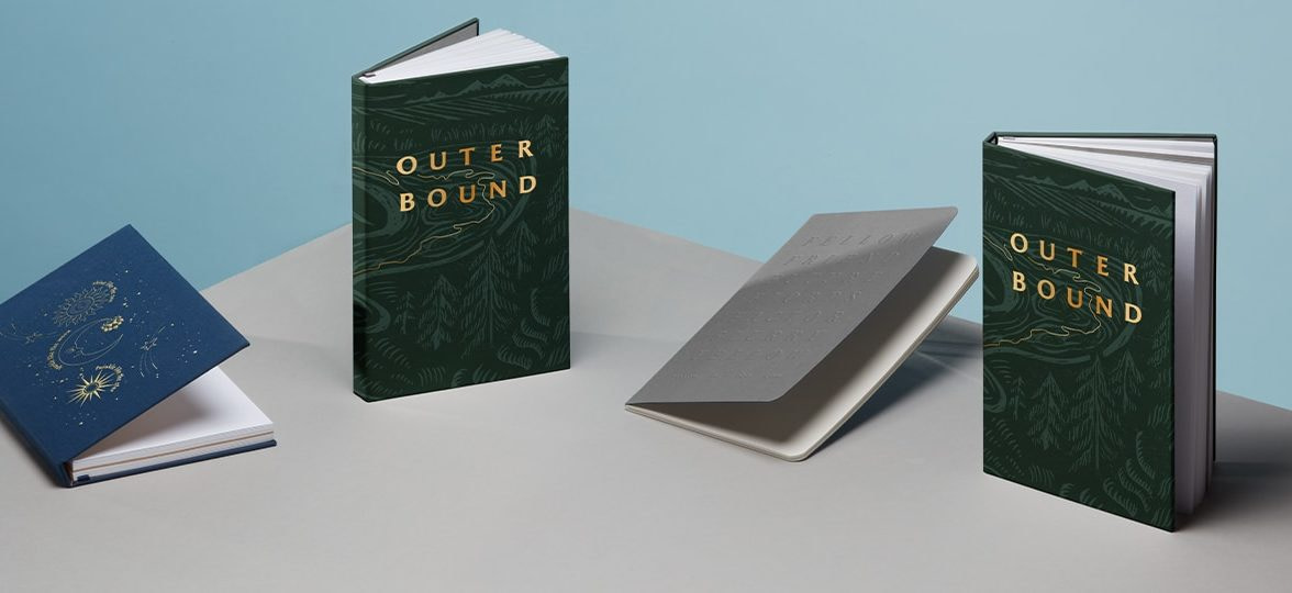 4 custom branded notebooks including a blue notebook with gold foil design, 2 green notebooks with gold foil and one grey softcover notebook