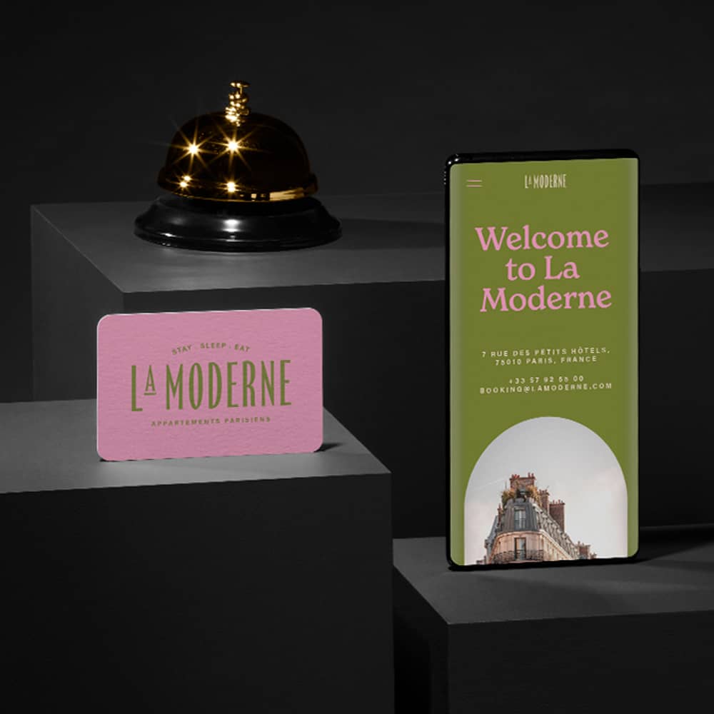 A business card and mobile website on a phone shows the branding of a hotel. Next to them sits a service bell.