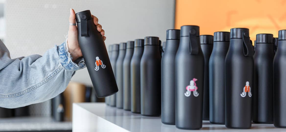 Employee taking a branded water bottle from a selection of different bottles