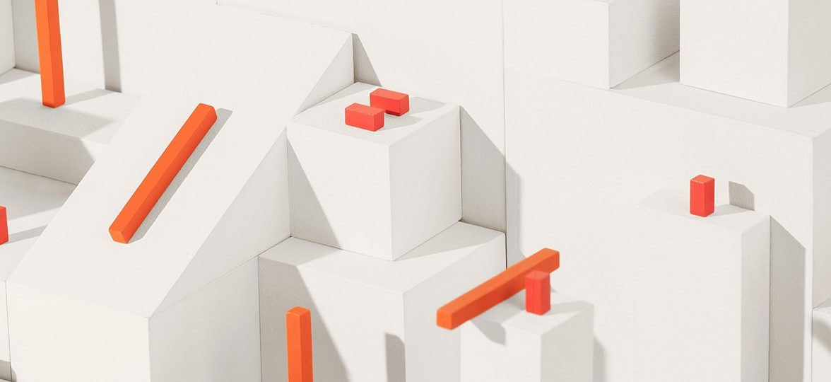 Orange building blocks in different shapes and sizes on white cubes