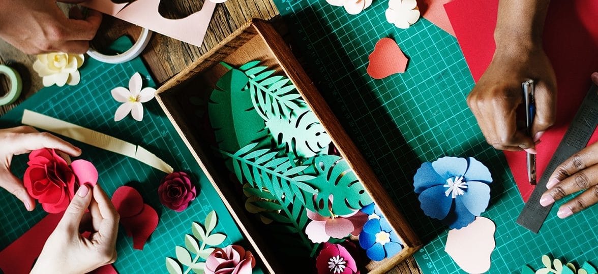 People cutting out paper shapes at a crafts table