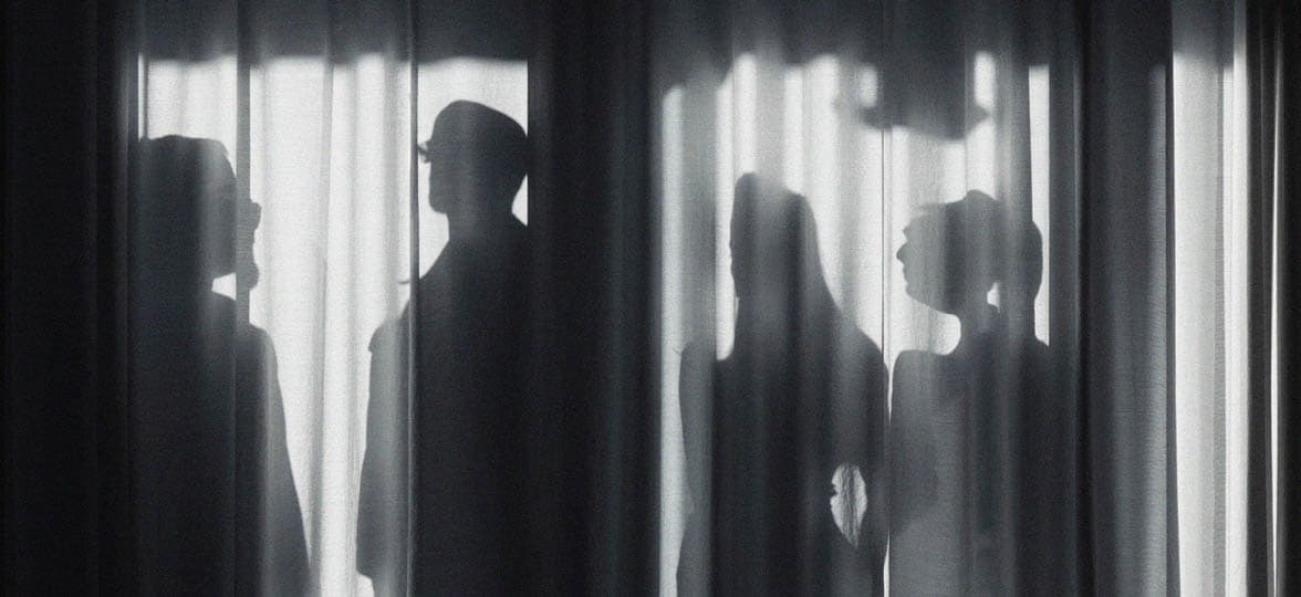 Black and white picture of a group of people behind a curtain