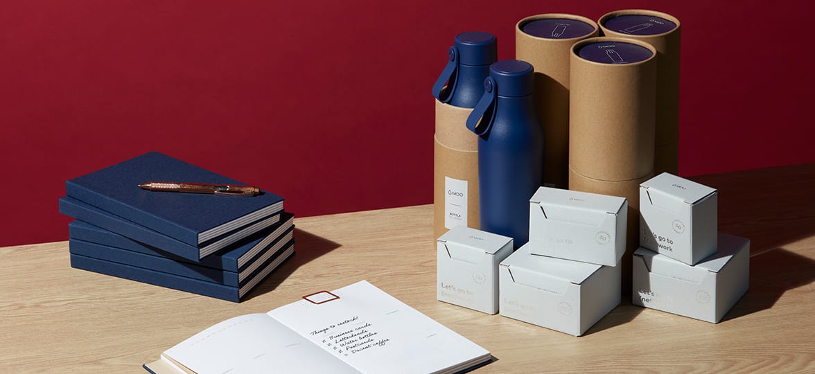 A table with newly ordered office supplies, including boxes of business cards, some water bottles, and some planners.