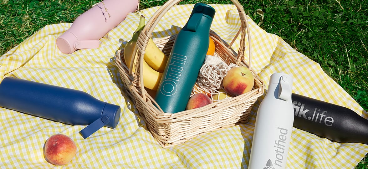 Custom water bottles with logos on a summer picnic blanket