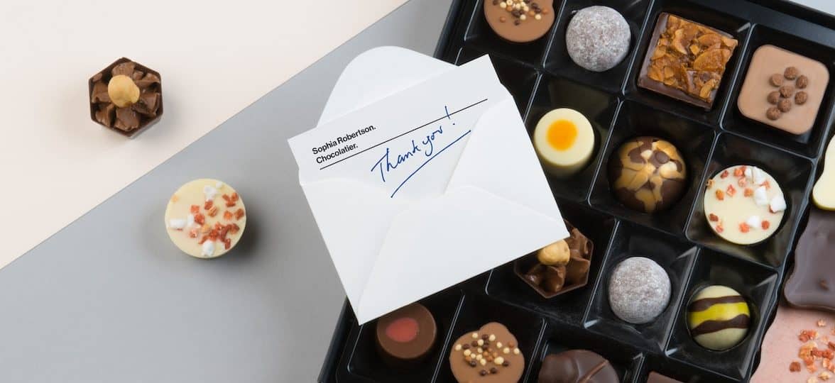 Thank you handwritten note in envelope on a box of chocolates