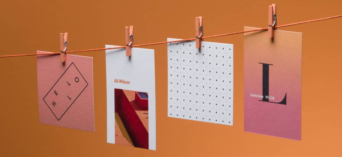 4 business cards in various designs hanging from a laundry line