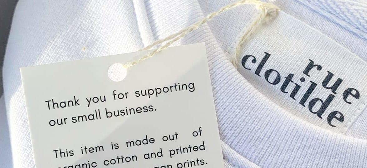 Close-up of Rue Clotilde white tshirt with hang tag explaining the sustainable production process