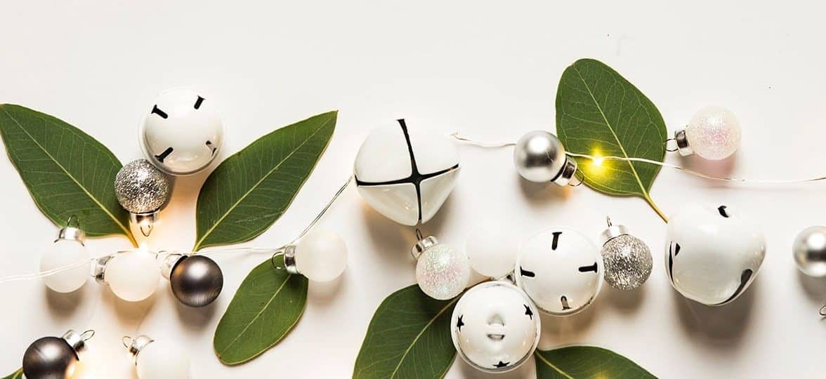 Leaves, bells, and white Christmas baubles on a white background