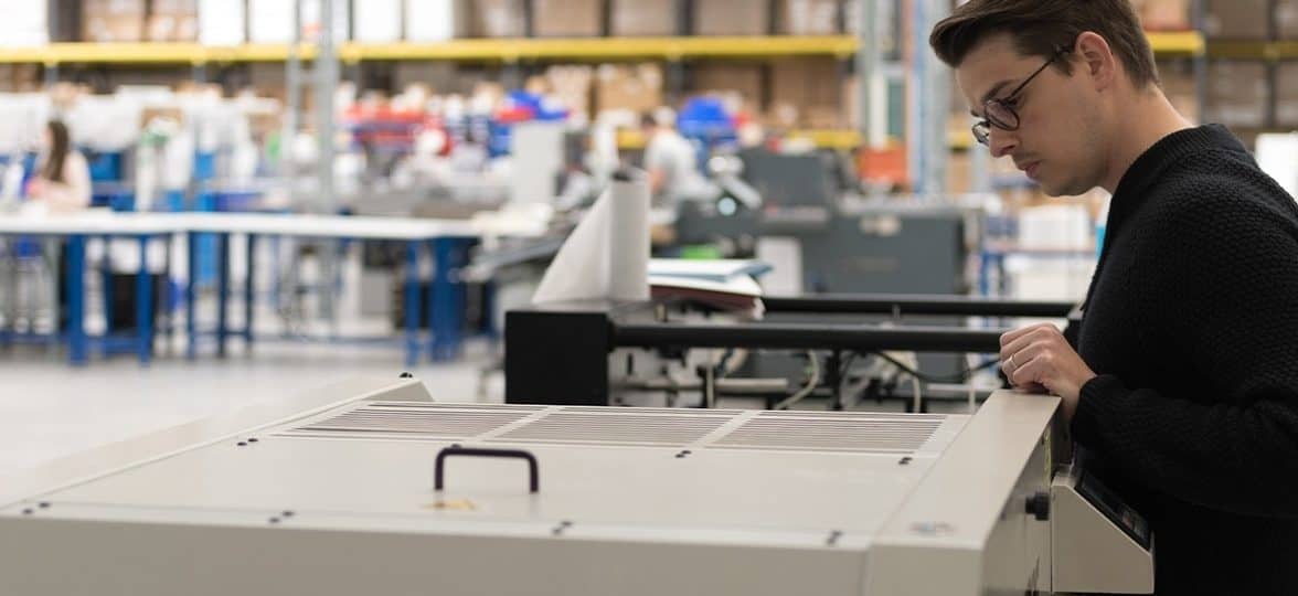 Man working on a printer at the MOO manufacturing facility