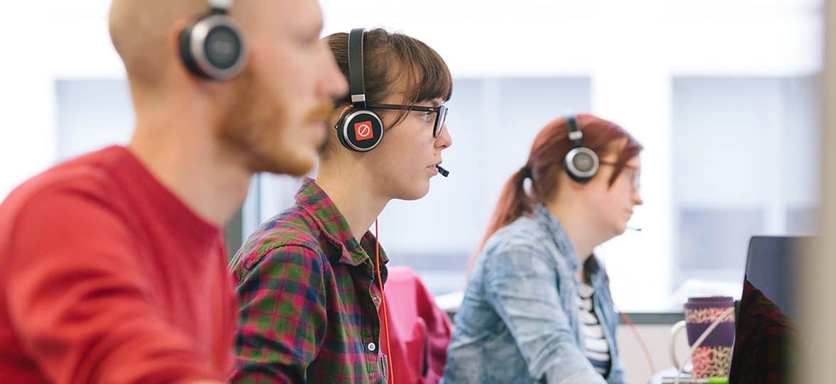 Three customer service reps sat next to each other with headsets