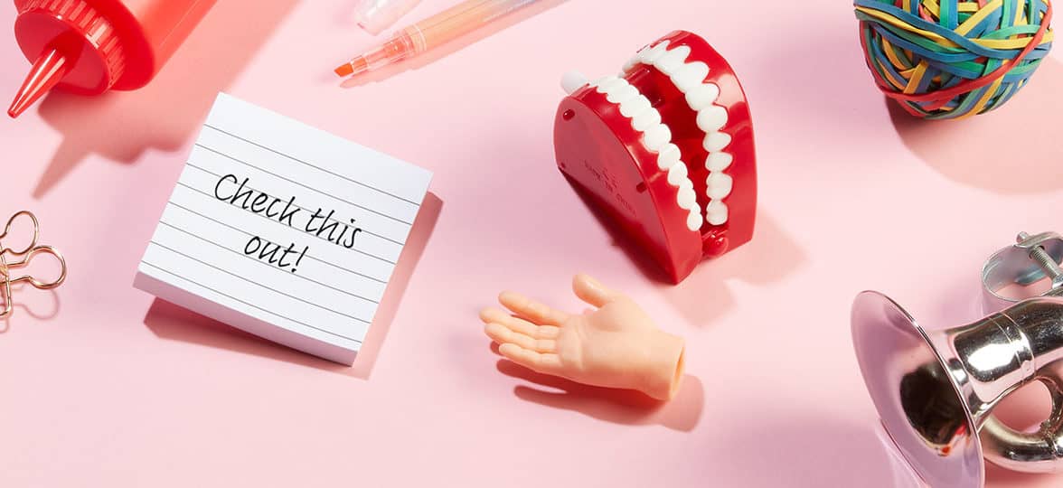 Various objects on a pink desk and note saying check it out