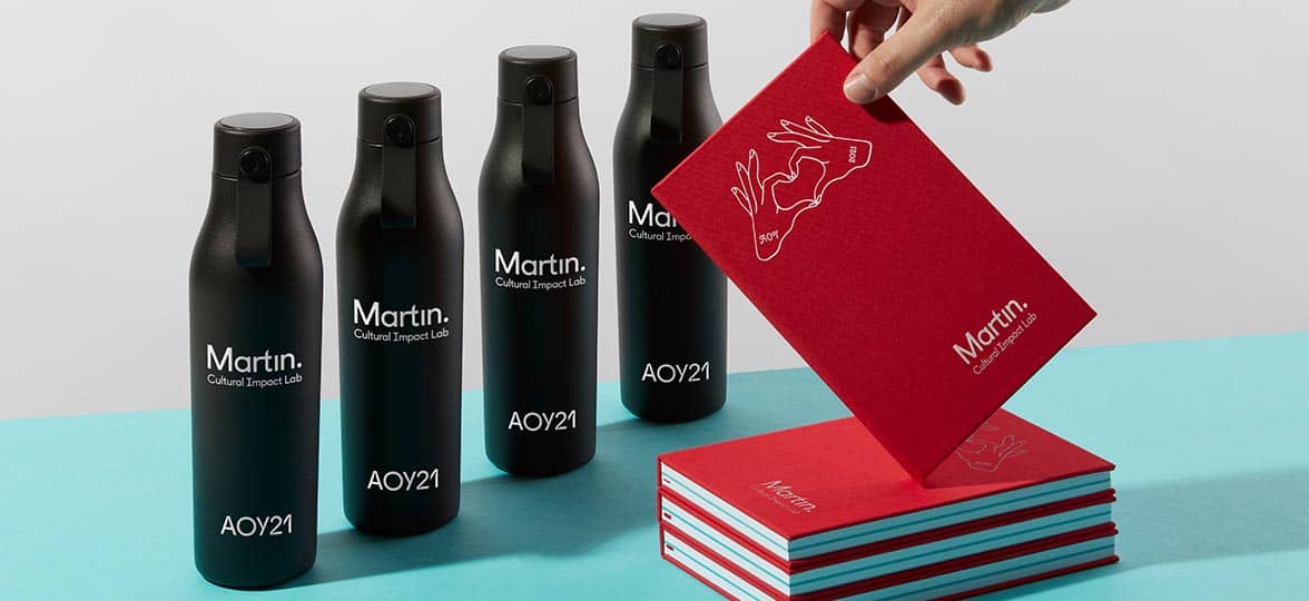 Black water bottles and red notebooks by Martin Agency and MOO