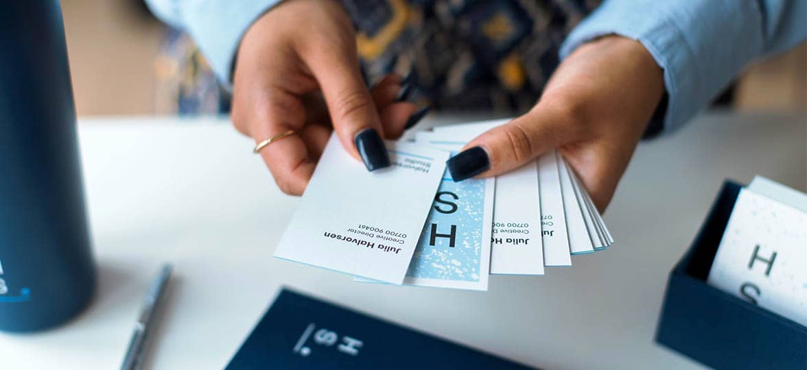 Hands with painted nails holding premium business cards with various font sizes