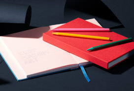 Open and closed notebooks on top of a desk with colorful pens.