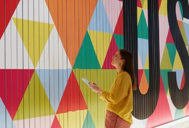 Woman looking at big colorful mural with a geometric pattern design and the word user written in big letters