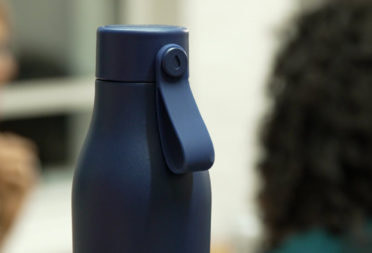 Blue MOO Water Bottle with people in the background