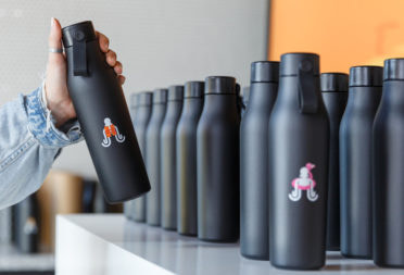 Employee taking a branded water bottle from a selection of different bottles