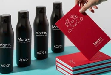 Black water bottles and red notebooks by Martin Agency and MOO