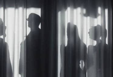 Black and white picture of a group of people behind a curtain