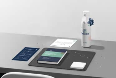 A desk with beautiful products like custom water bottle, branded notebook, and postcards on it