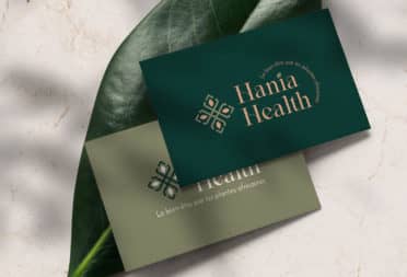 Two green business cards, one olive green and one dark pine green. They were designed by Roubina Tacorie for Hania Health