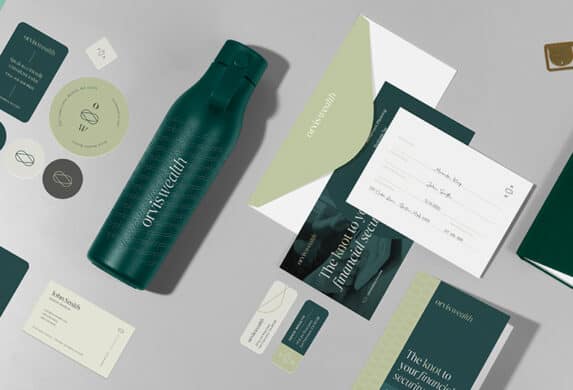 A suite of beautifully branded products laid out on a table, like water bottles, notebooks, envelopes, stickers, and business cards.