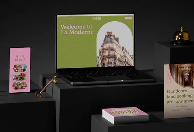 A suite of flyers, business cards, and square postcards for a modern hotel sit next to a lap top and cell phone showing matching branding on the hotel website built with Squarespace.