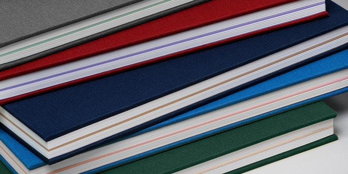 Pile of hardcover notebooks with cloth cover in various colors
