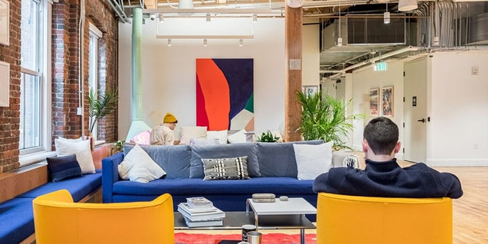 WeWork Boston office with a blue sofa, yellow chairs, plants and a big colorful painting