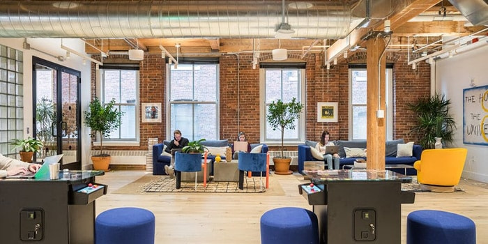 Boston WeWork office with brick walls and people working from blue couches and chairs