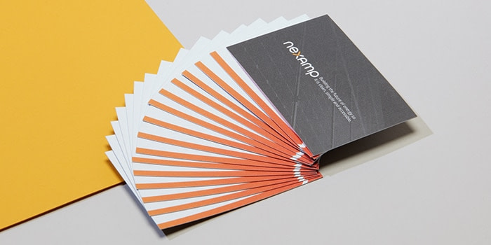 Nexamp cotton business cards fanned out so we see an orange line at the bottom of the design
