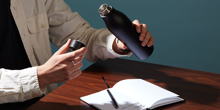 Man opening a black water bottle at their desk