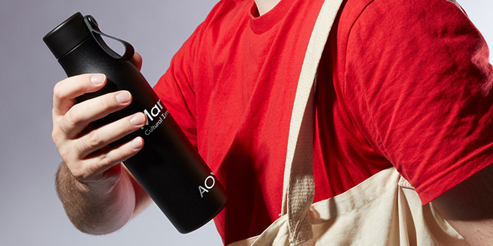 Person with red tshirt holding a black water bottle with Martin Agency's logo