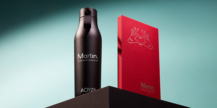 Black water bottle and red notebook with custom designs by Martin Agency and MOO