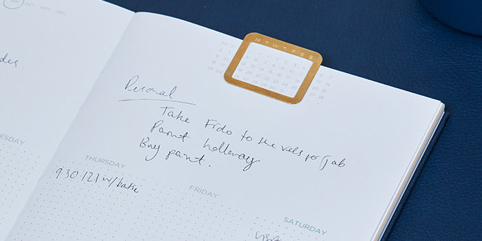 Close-up on MOO's undated planner with handwritten notes and a calendar clip