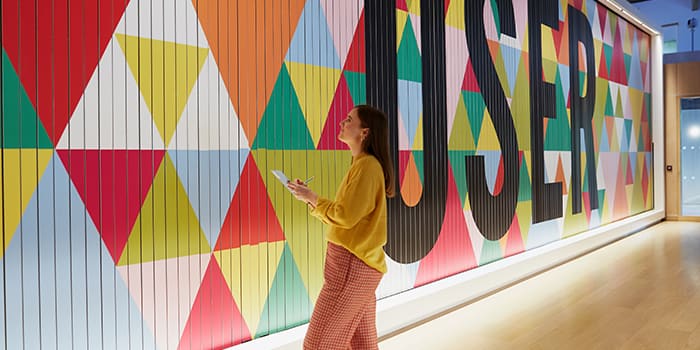 Em taking notes in front of a colorful mural with the word user