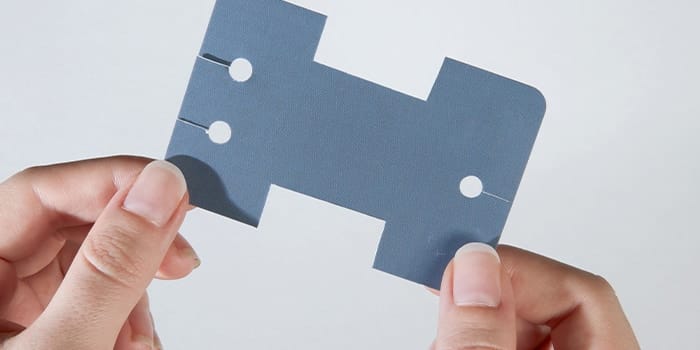 Hands holding a business card cut into an earphone holder