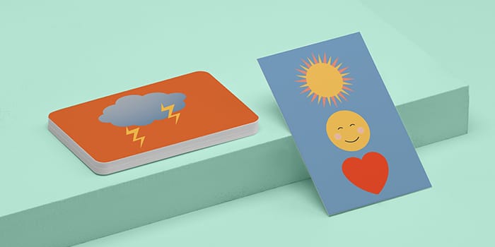 Stack of cards with storm emoji and blue card with sun, heart and smiling emojis