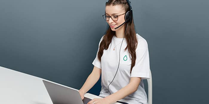 Person working at their laptop with a white tshirt and a headset
