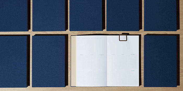 A gif that shows a grid of navy blue planners, with one planner opened to a blank page. Over time, each closed planner disappears until only the open planner is left.