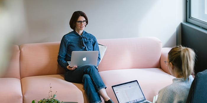 Customer service representative sat on a couch working on their laptop